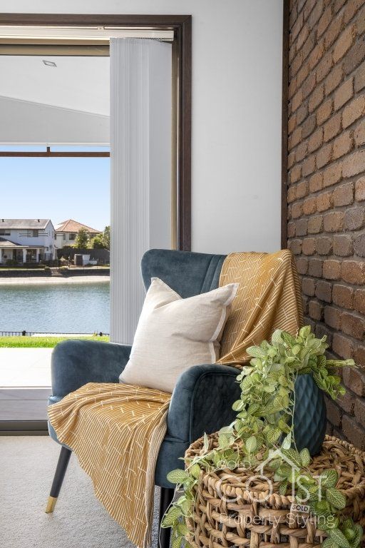 A chair with a blanket on it is in a living room next to a window.