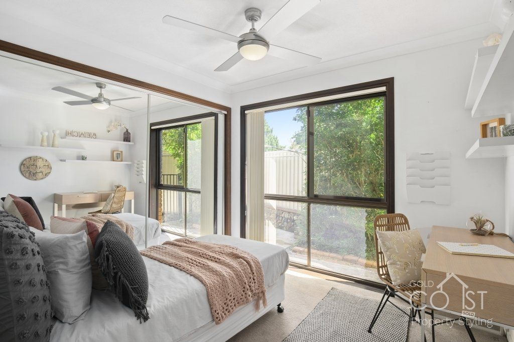A bedroom with a bed , desk , chair and ceiling fan.