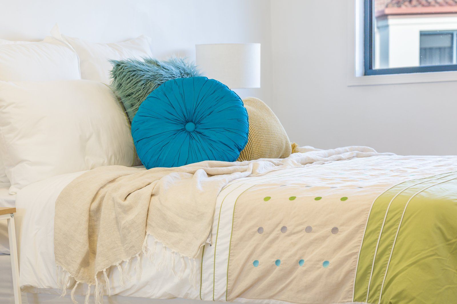 A bed with a blue pillow on top of it in a bedroom.