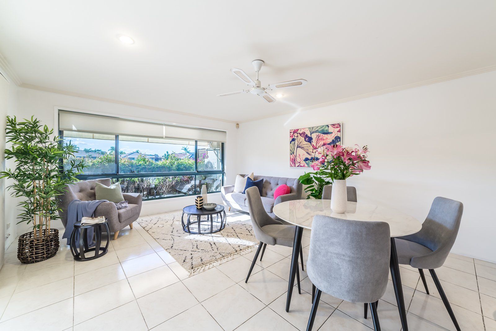 A living room with a couch , chairs , a table and a ceiling fan.