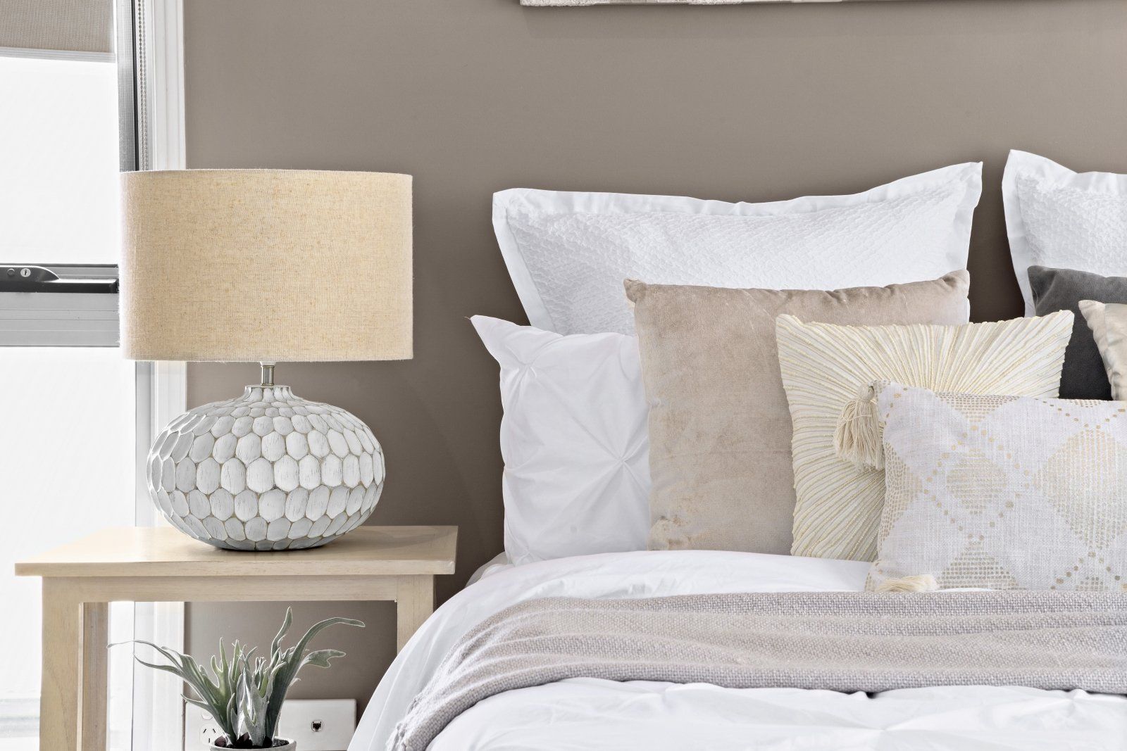 A bed with white sheets and pillows and a lamp on a nightstand