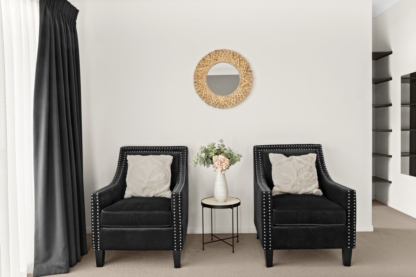 A living room with two black chairs and a mirror on the wall