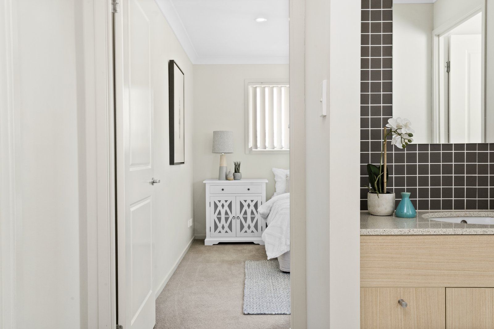A hallway leading to a bedroom and bathroom in a house.