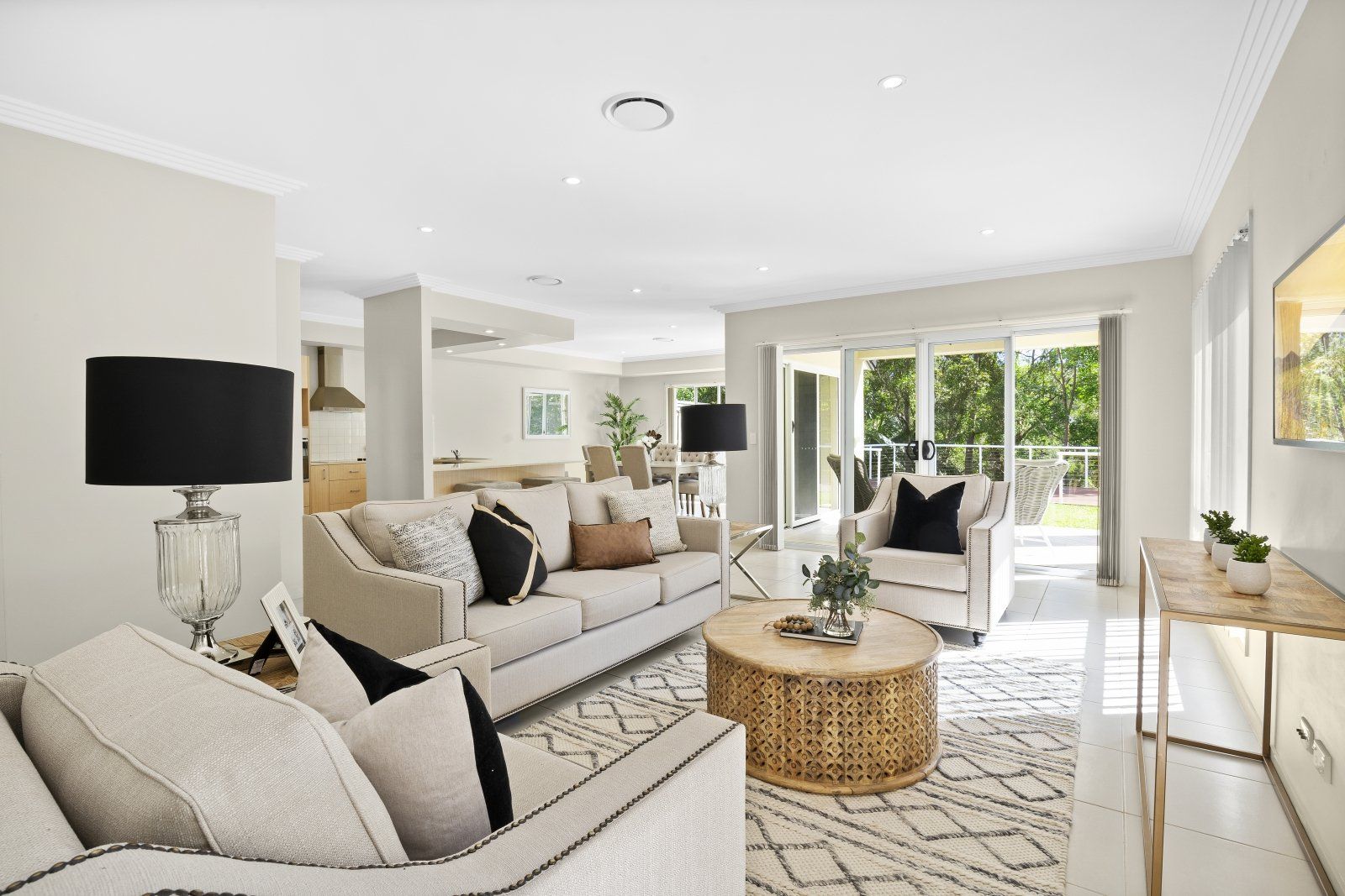 A living room with a couch , chairs , coffee table and lamps.