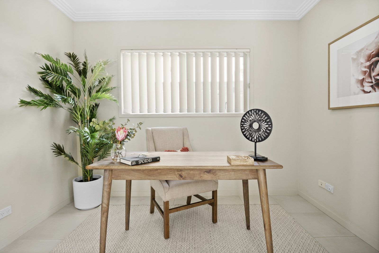 A home office with a desk , chair , plant and fan.