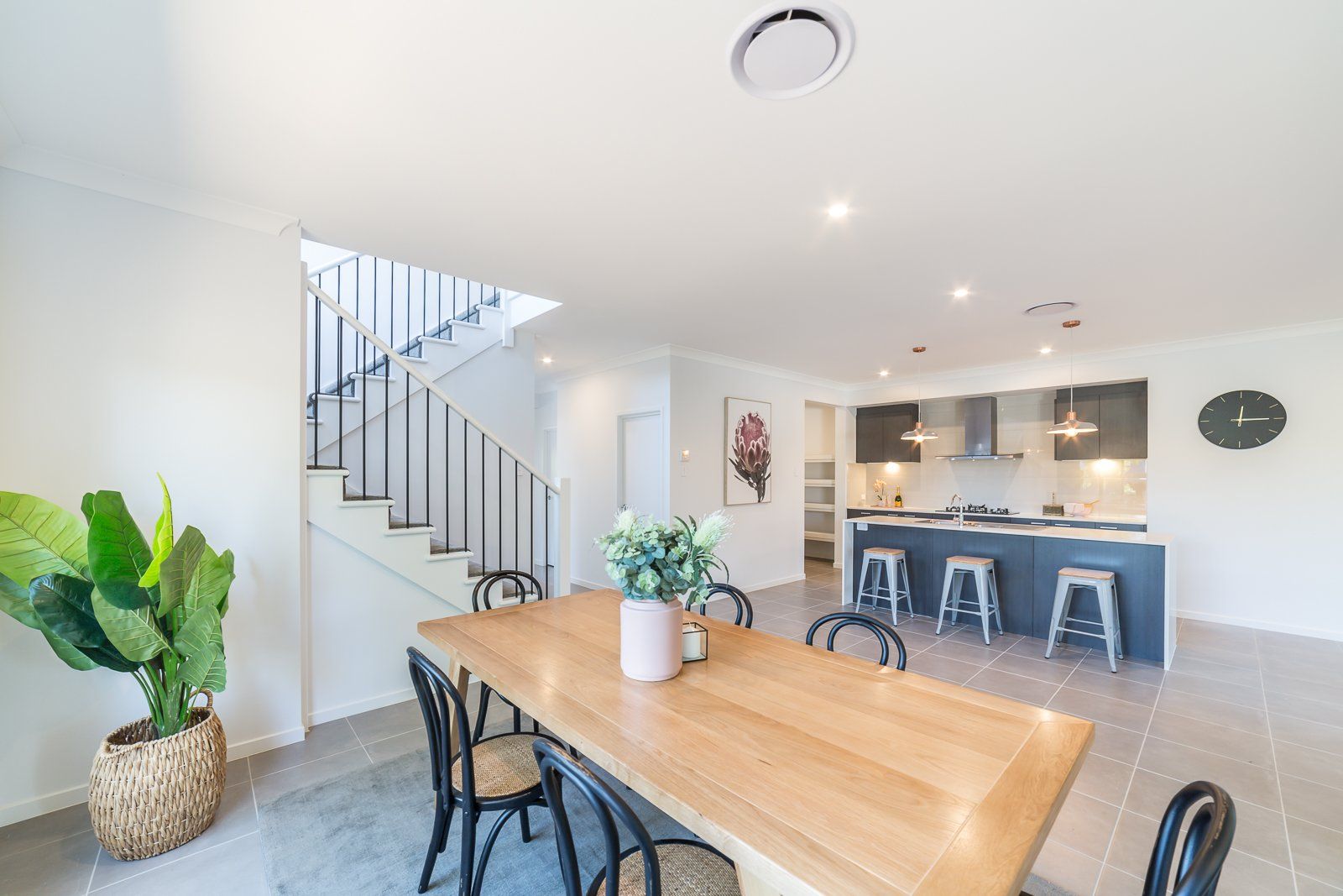 A dining room with a wooden table and chairs and a kitchen.