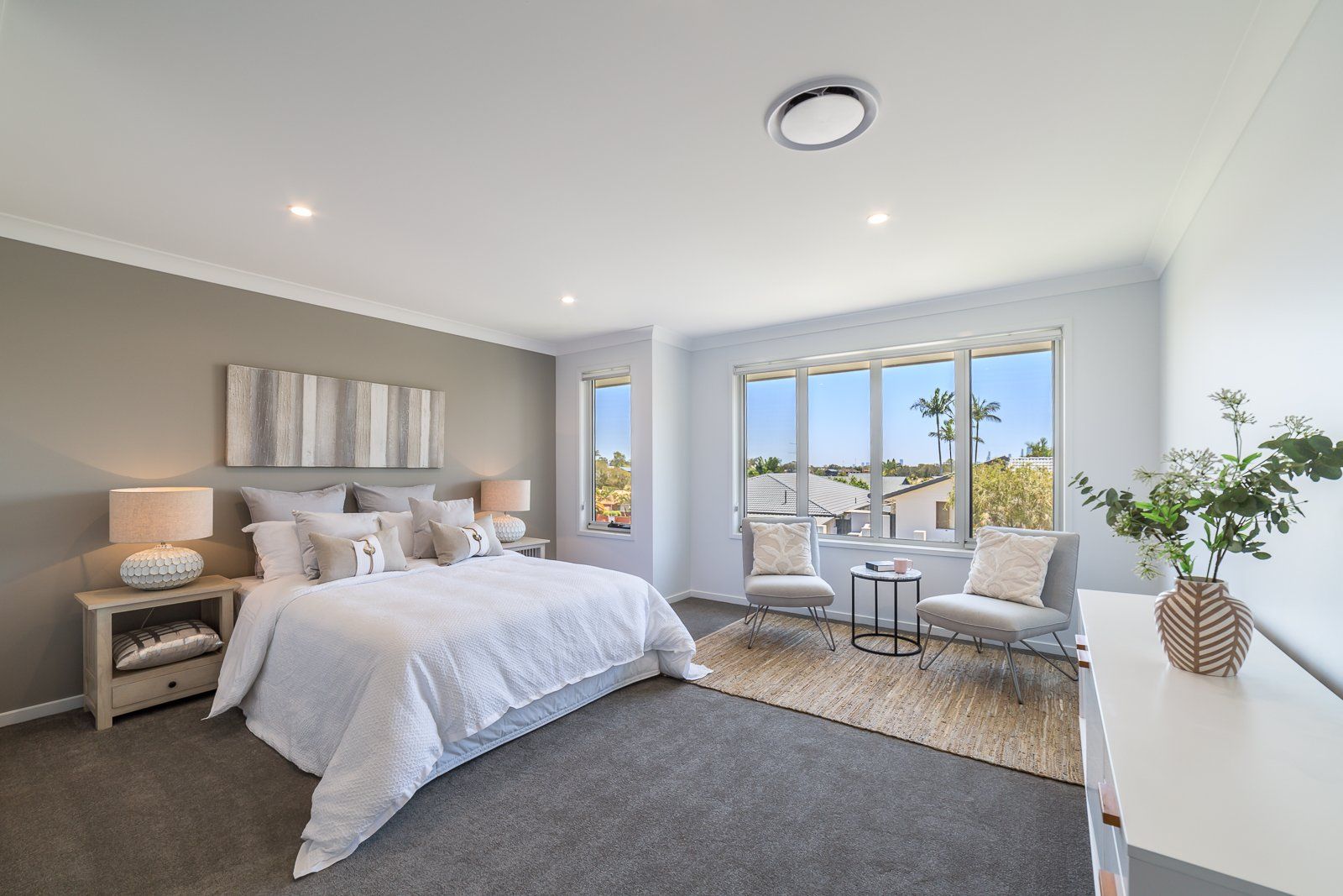 A bedroom with a king size bed , chairs , lamps and a table.