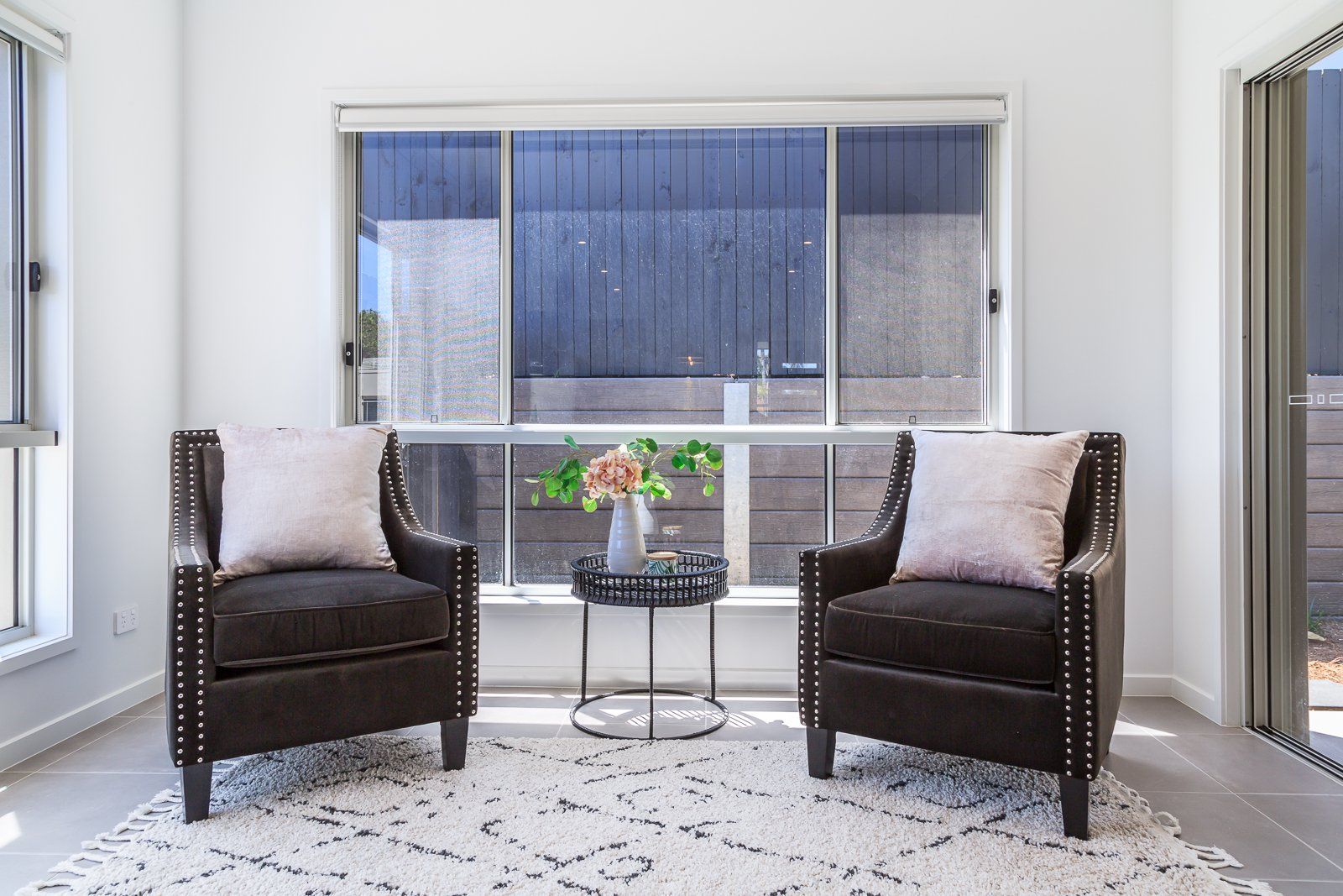 A living room with two chairs and a table in front of a window.