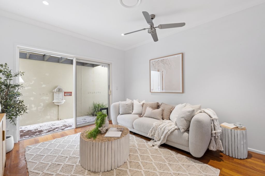 A living room with a couch , coffee table , and ceiling fan.