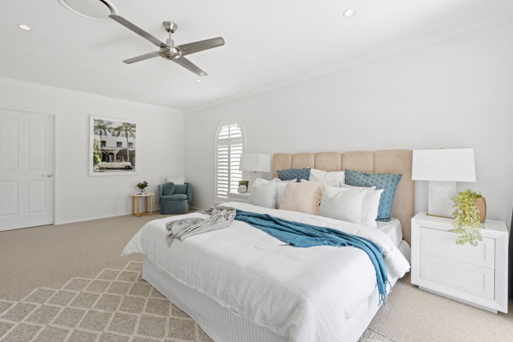 A bedroom with a large bed and a ceiling fan.