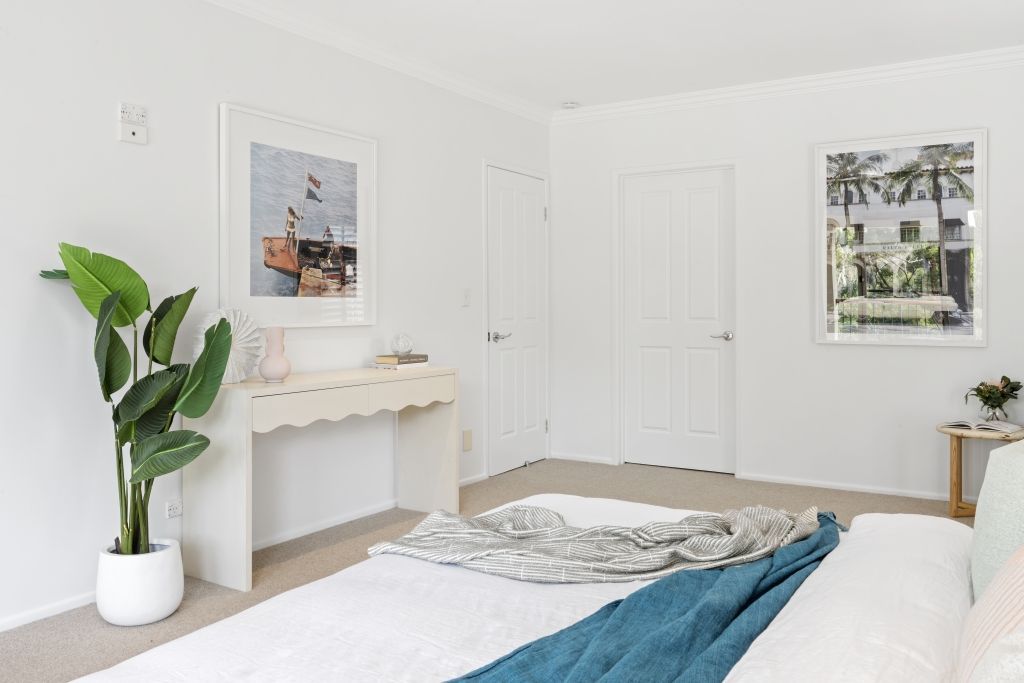 A bedroom with a bed , a plant , and a picture on the wall.