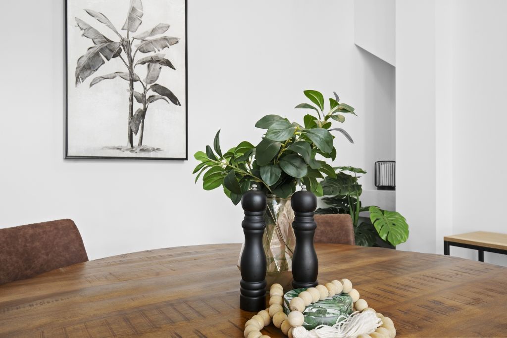 There is a picture of a banana tree on the wall above the table.