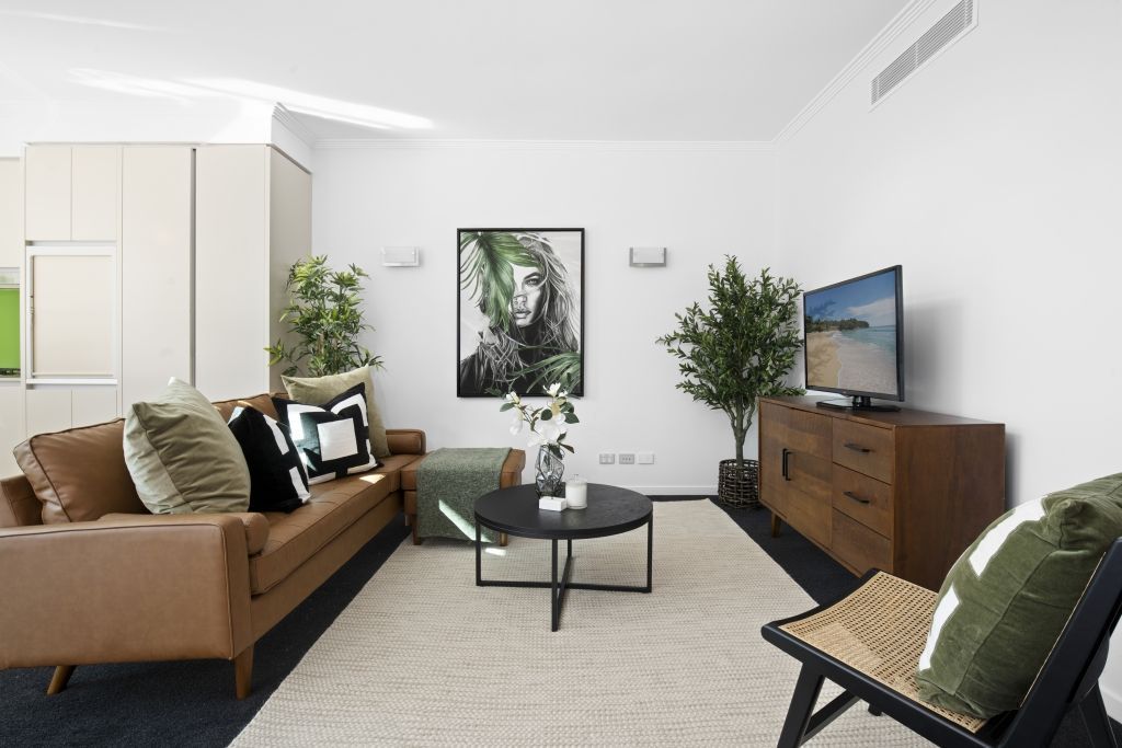 A living room with a couch , chair , coffee table and television.