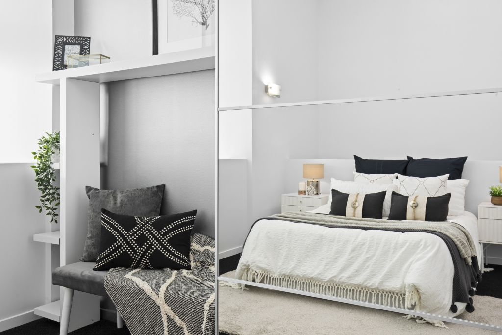 A bedroom with a bed , couch , and mirror.