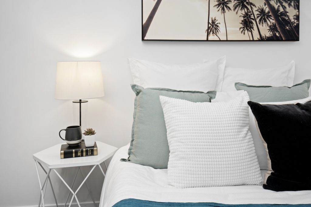 There is a picture of palm trees on the wall above the bed.