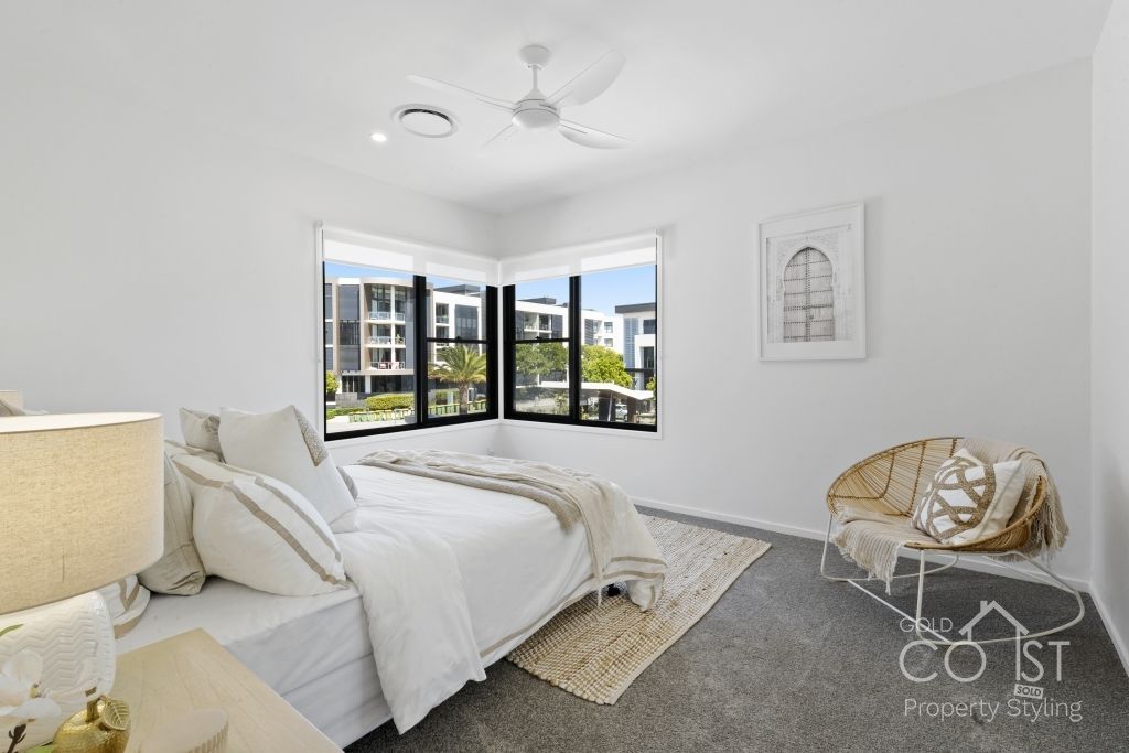 A bedroom with a bed , chair , lamp and ceiling fan.