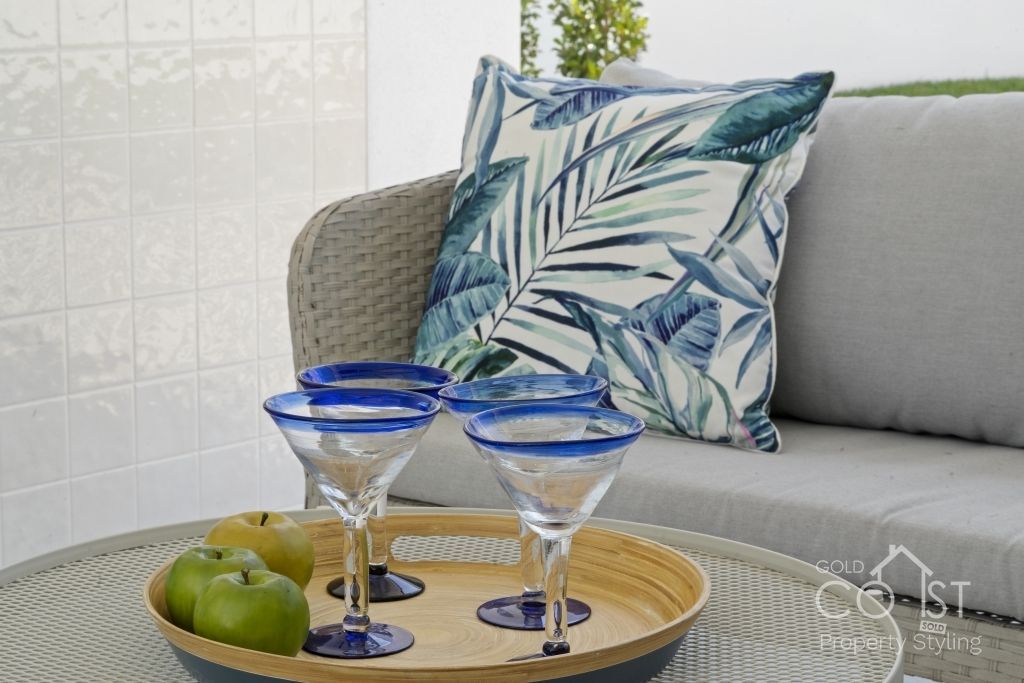 Three martini glasses are on a tray on a table next to a couch.