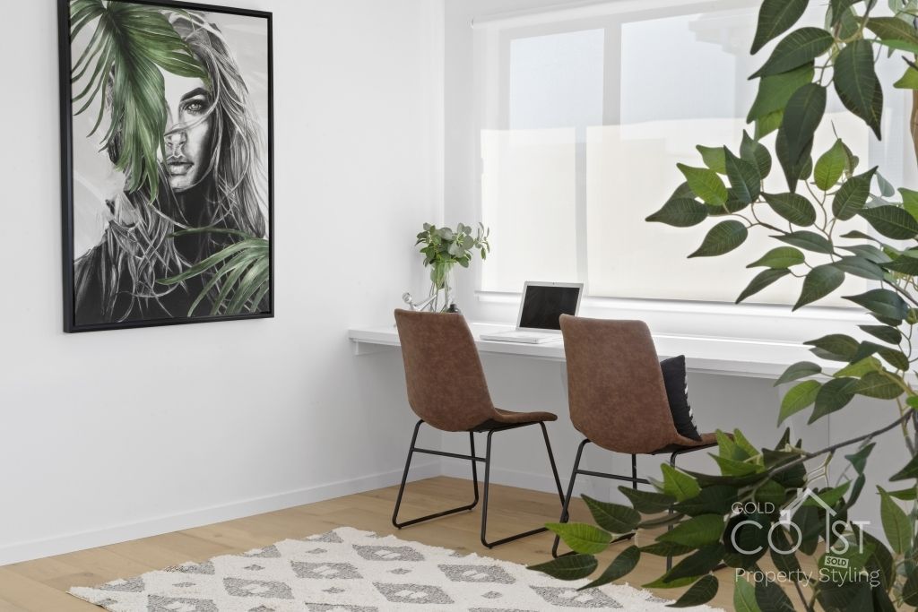 A room with two chairs , a desk and a painting on the wall.