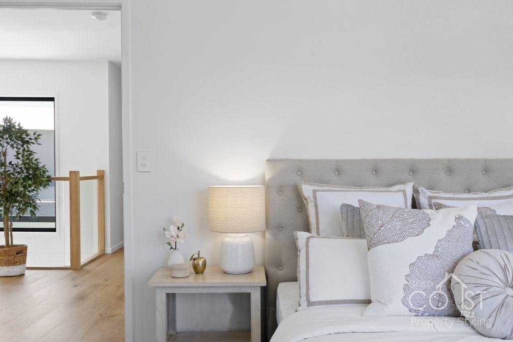 A bedroom with a bed , nightstand , lamp and window.