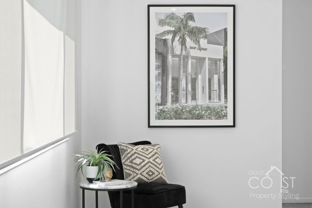 A living room with a chair , table and a picture on the wall.