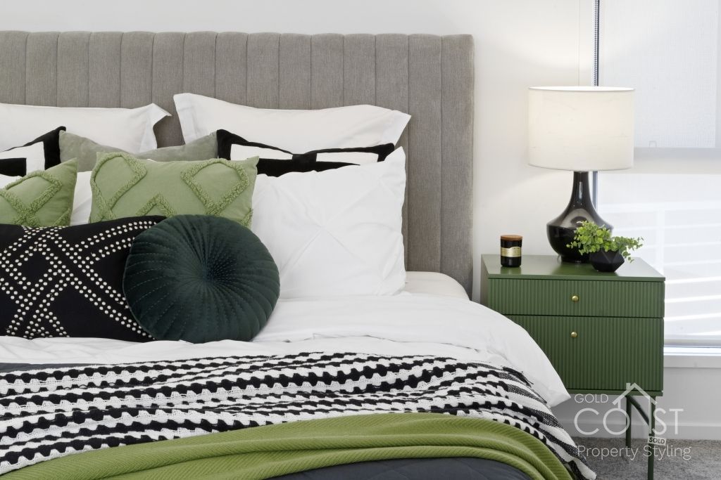 A bed with a green nightstand and a lamp