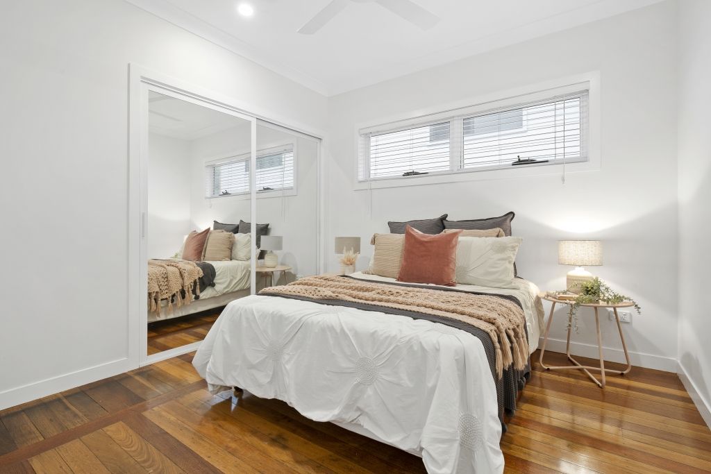 A bedroom with a bed , mirror and wooden floor.