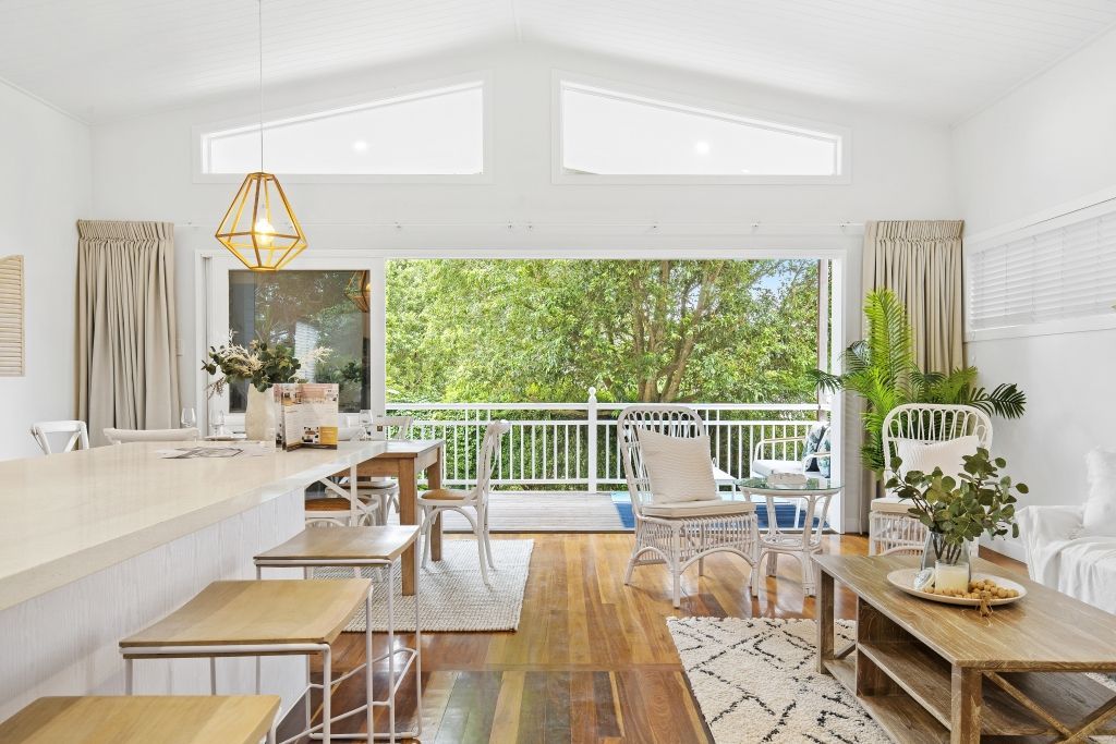 A living room filled with furniture and a balcony with trees in the background.