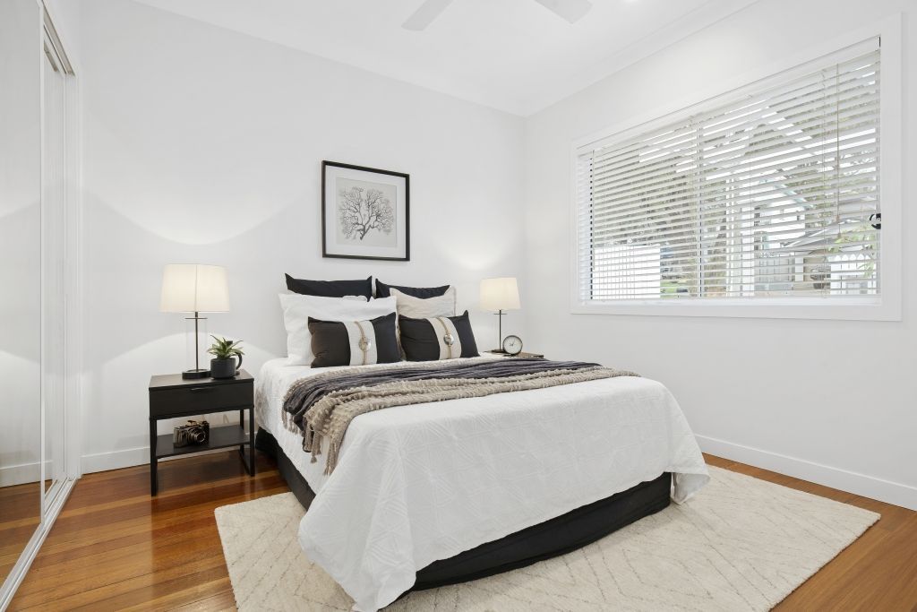 A bedroom with a bed , nightstand , lamps and a window.