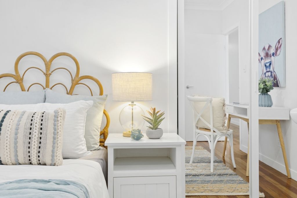 A bedroom with a bed , nightstand , lamp and desk.