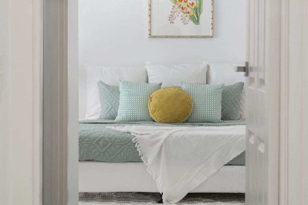 A bedroom with a couch and pillows and a picture on the wall.