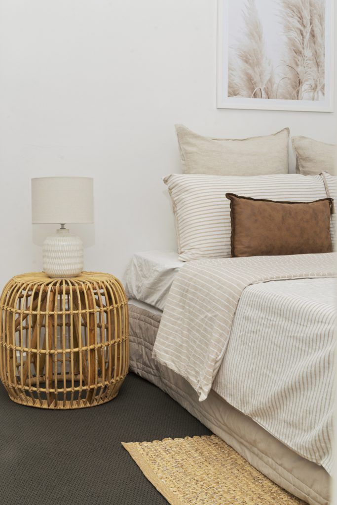 A bedroom with a bed , nightstand , lamp and rug.