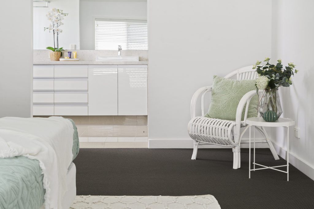 A bedroom with a bed , chair , table and bathroom.