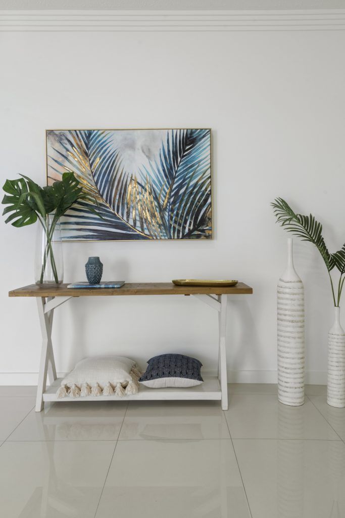 A living room with a wooden table and a painting on the wall.