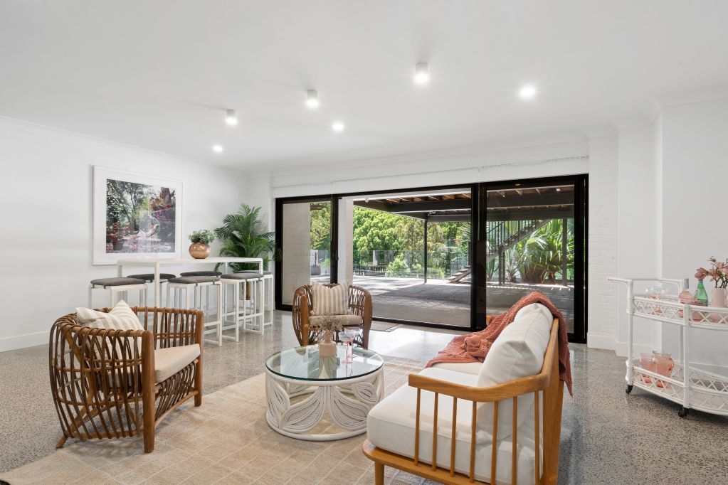 Bright modern living room with wicker chairs, sofa, coffee table, and large sliding glass doors.