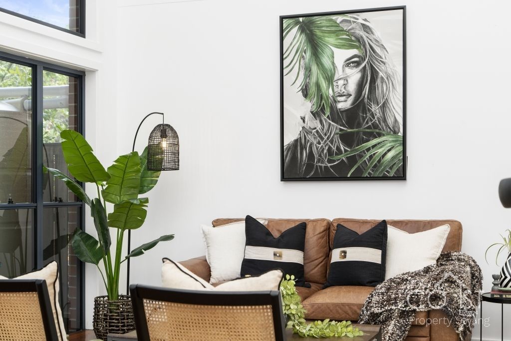 A living room with a couch , chairs , and a painting on the wall.