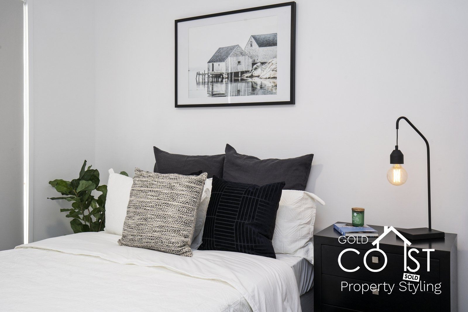 A bedroom with a bed , nightstand , lamp and picture on the wall.
