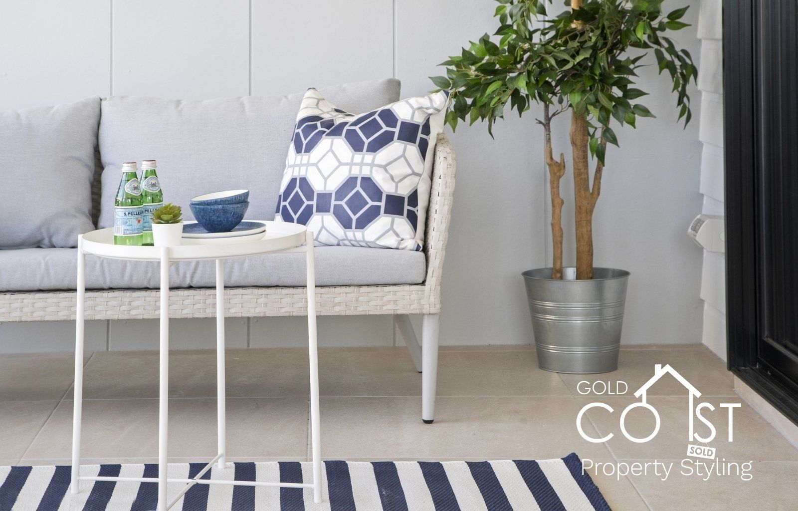 A living room with a couch , table , and potted plant.