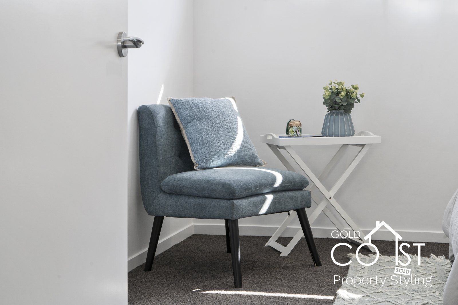 A chair in a room next to a table with a vase of flowers on it