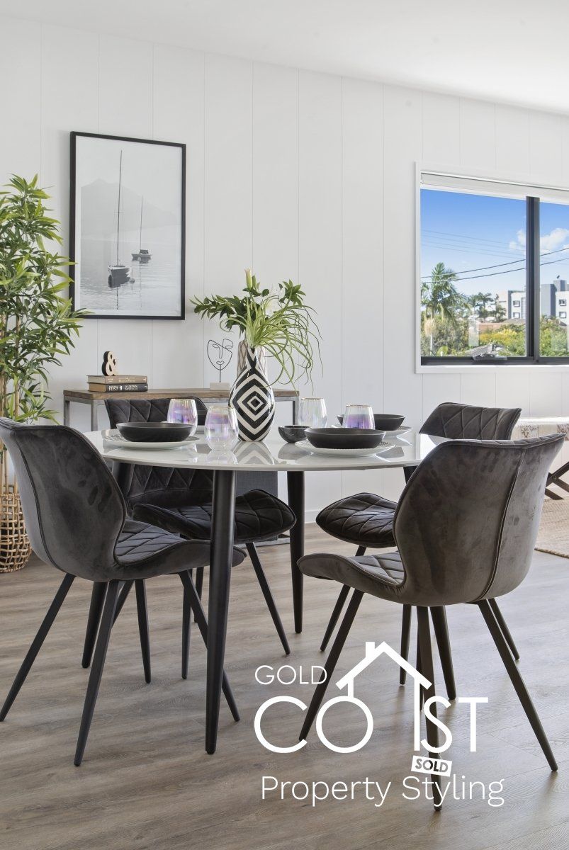 A dining room with a table and chairs and a picture on the wall.