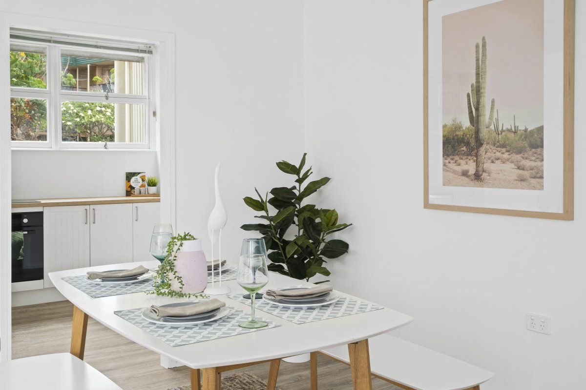 There is a picture of a cactus on the wall above the dining table.