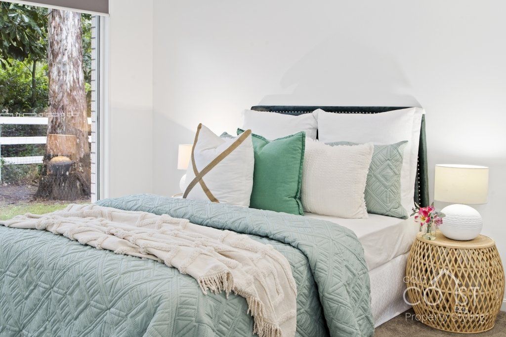 A bedroom with a bed , nightstand , lamp and window.