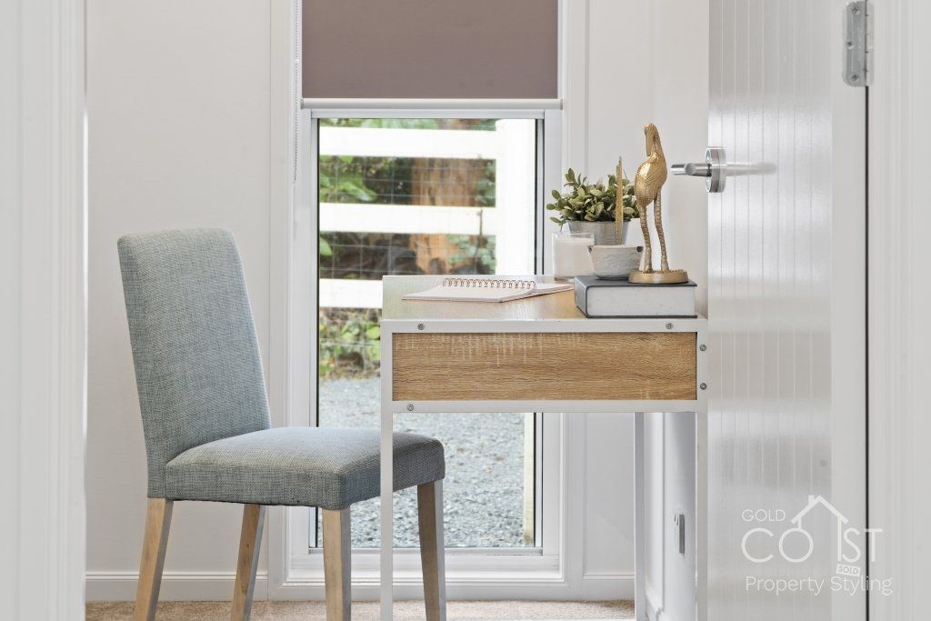 A room with a desk and chair in front of a window.