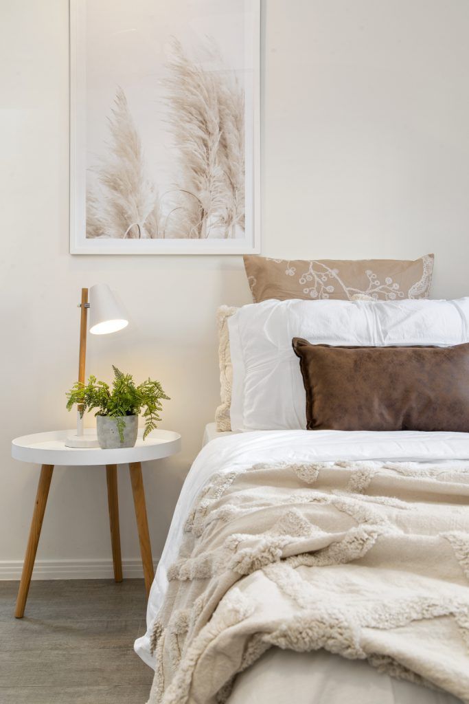 A bedroom with a bed , nightstand , lamp and painting on the wall.