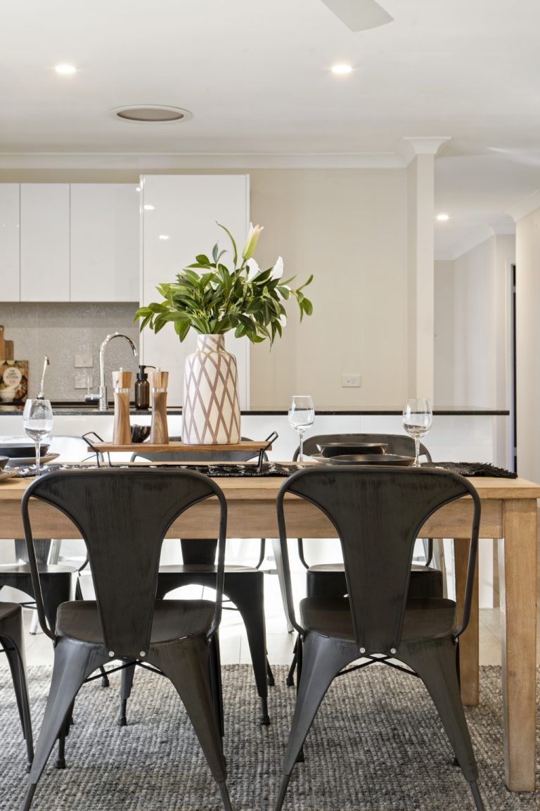 A dining room table with black chairs and a vase of flowers on it.