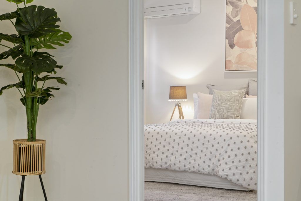 A bedroom with a bed , lamp , and potted plant.