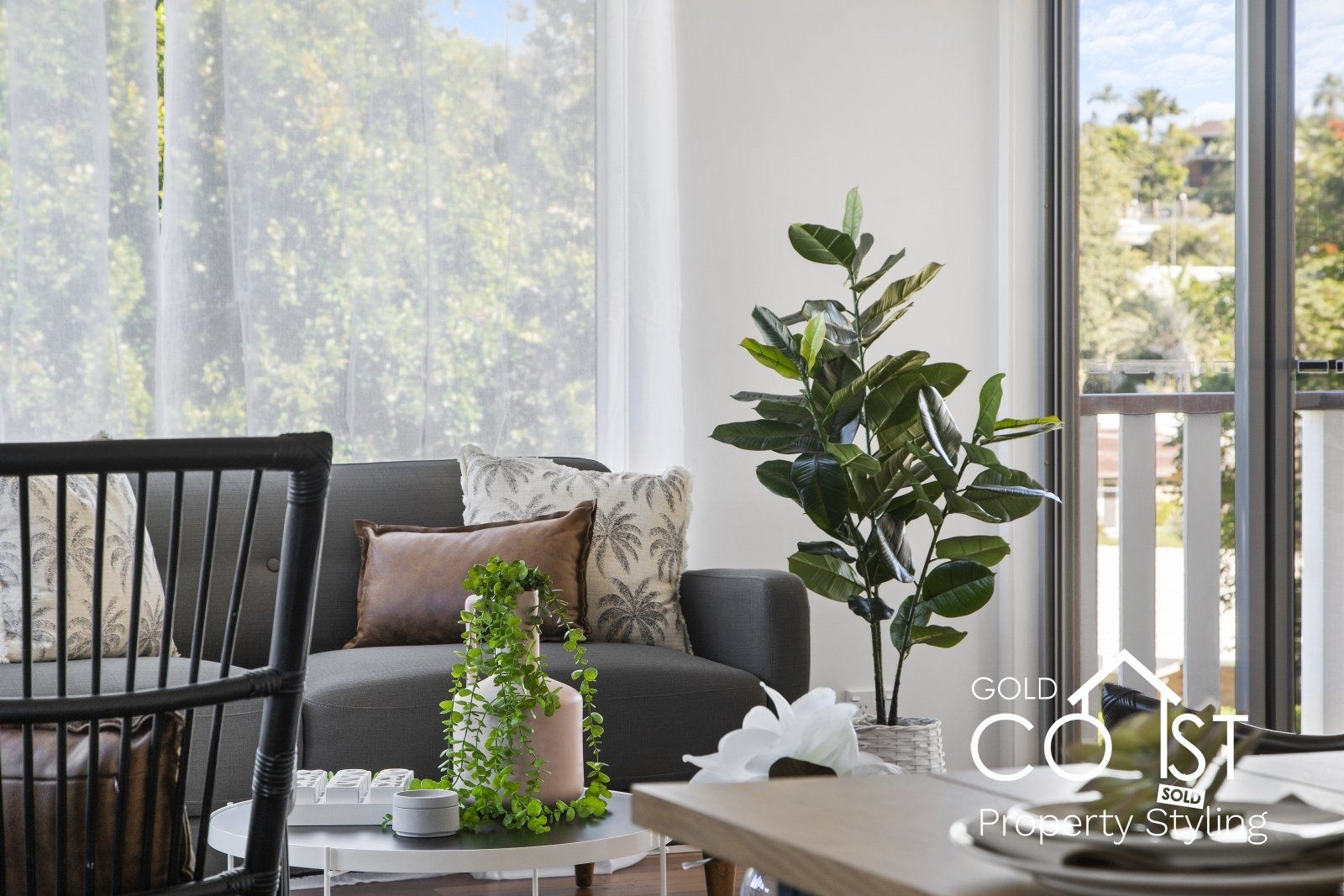 A living room with a couch , chair , table and potted plant.