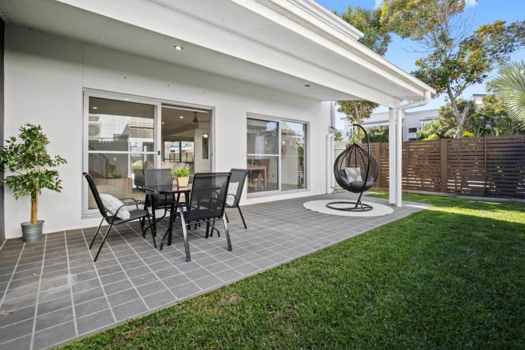 A patio with a table and chairs in the backyard of a house.