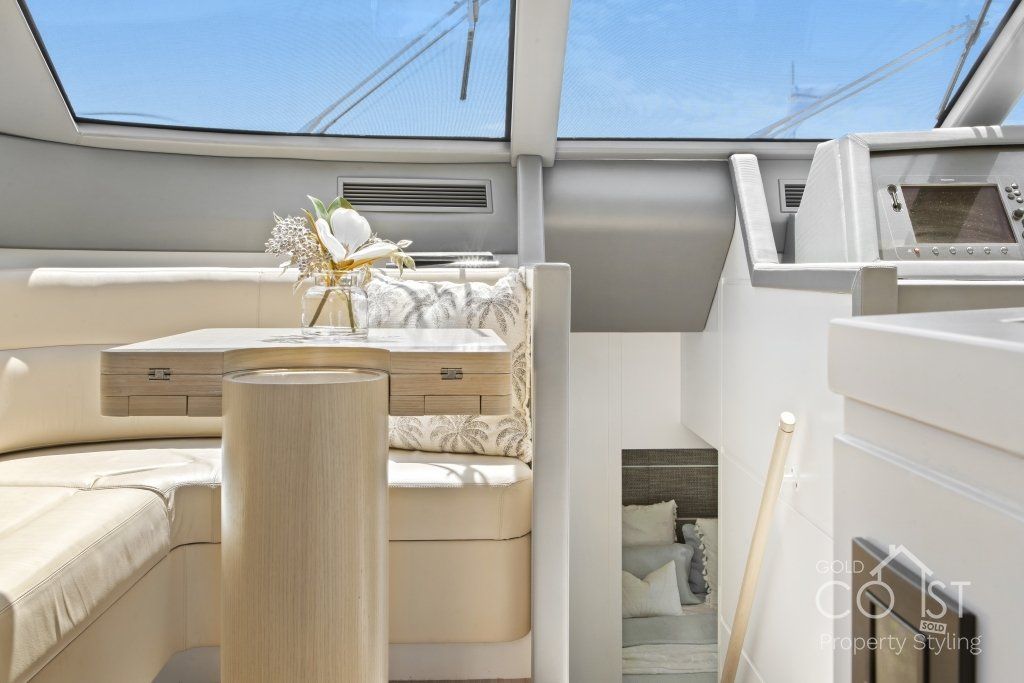 A living room on a boat with a table and a window.