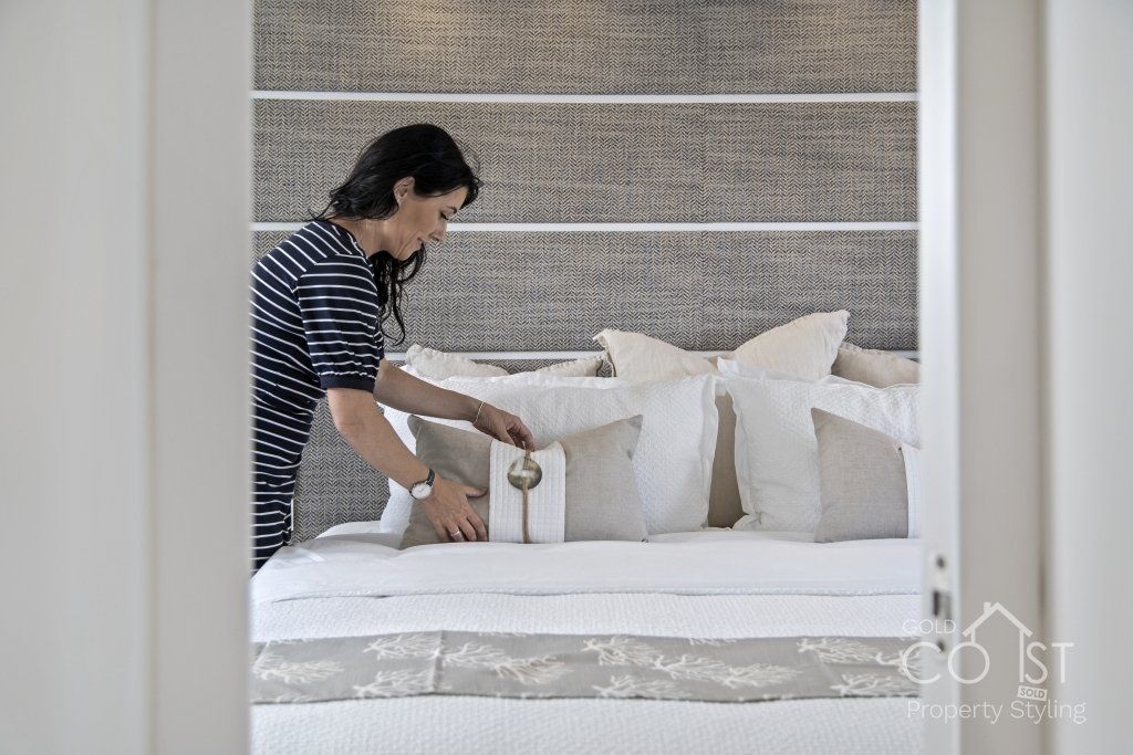 A woman is making a bed in a bedroom.