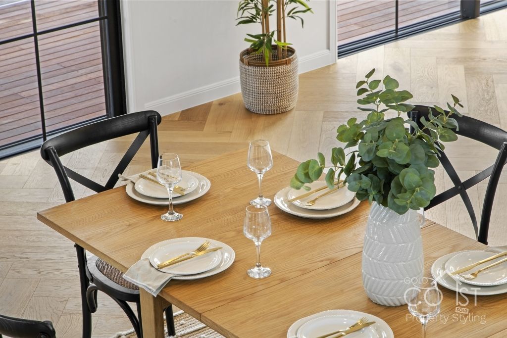 A dining room table with plates , glasses , and a plant on it.